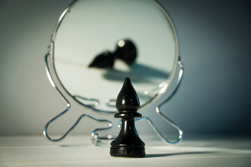 A chess piece is reflected in the mirror. Things and people are not what they seem. Reassessment of...