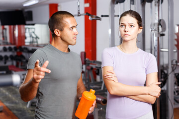 Fototapeta premium Personal trainer and young woman having emotional conversation at sports club