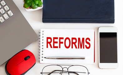 REFORMS text on notepad,pen, office tools on the white background. Business concept