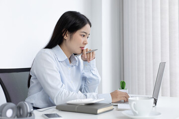 Young white Asian woman studying via the internet in her home office.