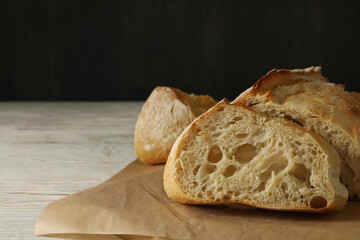 Baking paper with bread on white wooden background