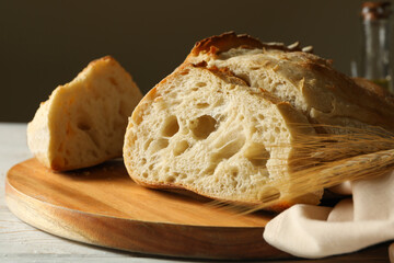 Board with fresh bread on white wooden background