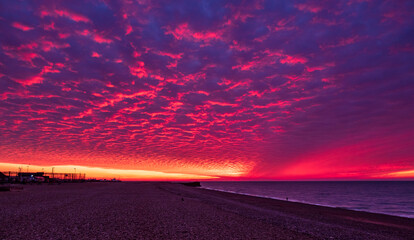 Dramatic November red dawn and mackerel clouds sky over Hastings beach front in east Sussex south east England