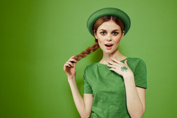 Nice girl with a shamrock on her hand on a green background holidays St. Patrick's Day fun hat on her head