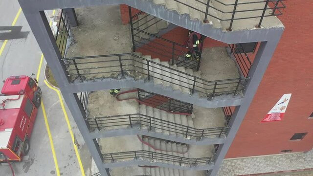 Fire fighters carry fire hose to fire ground in stairs.  Aerial view of emergency rescue operation.