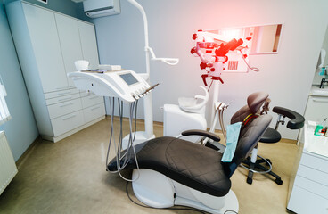 Dentist chair in modern clinic. Dental microscope for surgery. Up to date equipment. Oral care concept.
