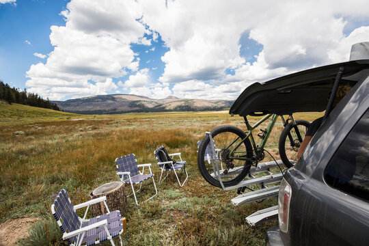 A row of folding chairs and an SUV with bike rack and bicycle. 