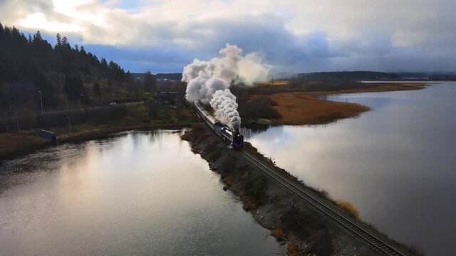 Historic Old steam touristic locomotive train with a wagons rides going in green forest. there is black grey smoke. Russia, Karelia, Sortavala. Flying over. Aerial view. Drone is standing