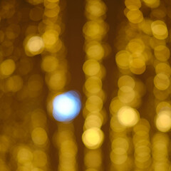 Fototapeta premium Blurred light background of christmas garlands, golden bokeh of city street lamps
