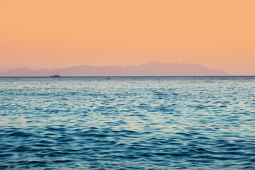 Mediterranean sea at sunset with silhouettes of ships and mountains in the distance