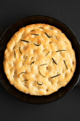 Homemade Rosemary Skillet Focaccia on a black surface, top view. Flat lay, overhead, from above.