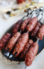 Top view of delicious traditional homemade Turkish grilled kebab /Kebap on skewers on the white table for dinner. Cuisine food culture in Turkey. Meat diet. Selective focus. 