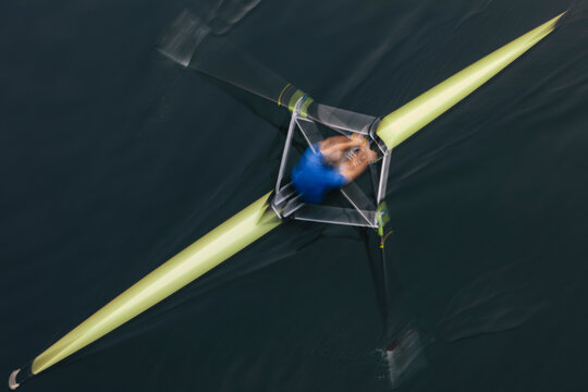 A single scull boat and rower on the water, view from above.