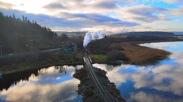 Historic Old steam touristic locomotive train with a wagons rides going in green forest. there is black grey smoke. Russia, Karelia, Sortavala. Flying over. Aerial view. Drone is standing