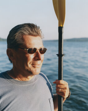 Portrait Of Middle Aged Man Holding Sea Kayak Paddle At Dusk