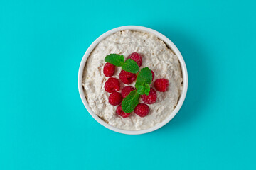 Bowl yogurt with raspberries and mint, on a blue background, no people, copy spase, horizontal,