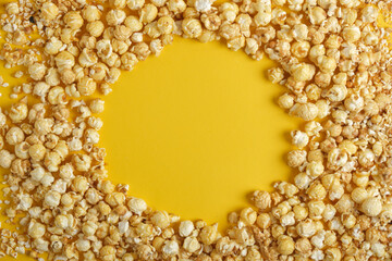 Frame made of caramel popcorn on yellow background