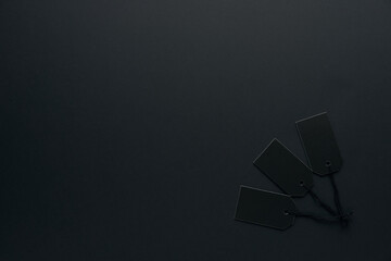 Blank black cardboard paper labels or price tags with cord isolated on dark background. Black Friday, Shopping, sale and marketing concept. Top view, flat lay, copy space. .