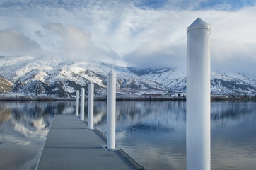 Pillars on dock at lake near snow covered mountain range