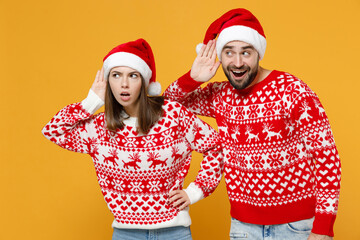 Curious young Santa couple friends man woman in sweater Christmas hat try to hear you overhear...