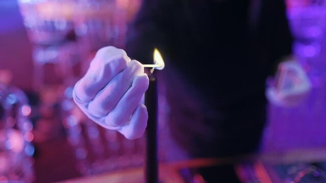 prepared table for an event. working man lights the candle with matches. party preparation.