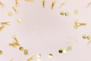 Fototapeta premium shiny gold clothespins and sequins on a pink background with a place to write. background for the holiday