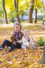 The elder brother and little sister are walking and laughing in the autumn park. Family and Children. Autumn mood
