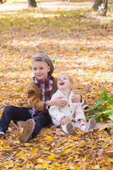 The elder brother and little sister are walking and laughing in the autumn park. Family and Children. Autumn mood
