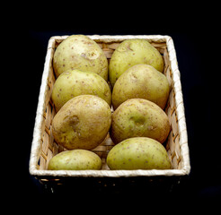 Cesto con patatas sobre fondo negro.