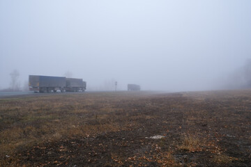 Fototapeta na wymiar Trucks are driving in the fog. Road with poor visibility.