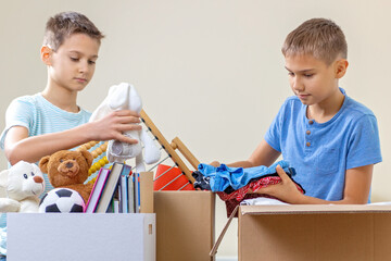 Kids volunteers sorting toys, clothes, books, donation goods in donate charity boxes
