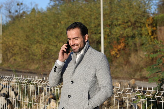 Stylowo ubrany przystojny, dojrzały  mężczyzna z telefonem na peronie.