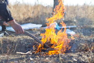cooking on an open fire. Frying food over a bonfire on a wooden branch - pricking spears in nature. Close-up of a hand. The scouts are preparing lunch.