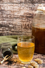 Kombucha, fermented healthy drink, served in a glass on a rustic background, with its ingredients. A concept of healthy life-style at home. 