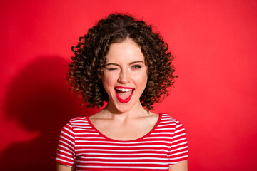 Photo of flirty funny wavy young woman dressed striped outfit winking open mouth isolated red color background