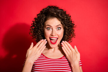 Photo of excited funny curly young lady wear casual striped outfit hands face open mouth isolated red color background