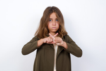 Beautiful little girl standing against white background,  has rejection angry expression crossing...