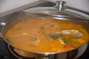 Boiling pot of Chraime, a traditional sephardic north African soup, with fish and vegetables, mainly butternut squash, cooked on the stoves.