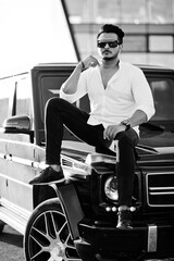 Fototapeta na wymiar Solid asian man in white shirt and sunglasses posed near black mafia suv car.