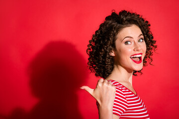 Photo of young cheerful happy young girl show point finger empty space present offer promotion x-mas isolated over red color background