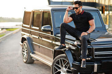 Asian man wear on all black posed near suv car.