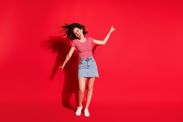 Full body photo of crazy active girl have fun enjoy point fingers empty space yell isolated over red color background