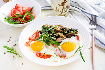 Tasty  breakfast - fried eggs, forest mushrooms, tomatoes and arugula. Lunch food.