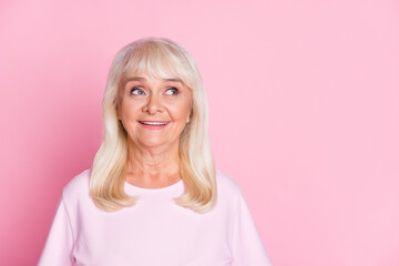 Photo portrait of curious smiling granny blonde hair looking at blank space wearing casual outfit isolated on pastel pink color background