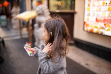 Little girl looking away from the camera with a Chinese restaurant behind her