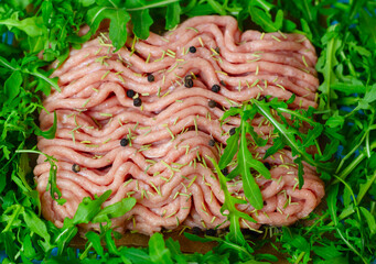 fresh ground turkey meat close up with pepper, rosemary, herbs arugula and spices