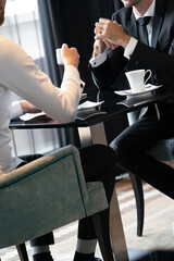 Image of young businessman with cup of coffee communicating with colleague