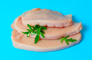 fresh turkey steaks with pepper and arugula on blue background