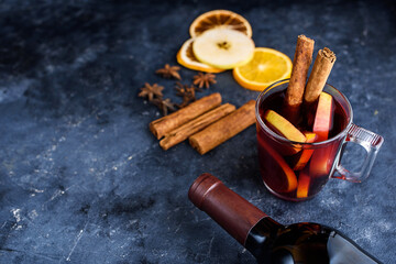 Mulled wine recipe ingredients on black chalkboard with text space - christmas or winter warming drink. Bottle of wine, honey, orange, cinnamon sticks, anise, nutmeg