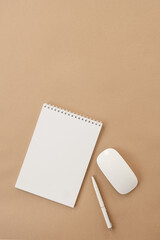 Flatlay of blank sheet spiral notebook, mouse, pen on pastel beige table. Flat lay, top view. Copy space mockup template background.